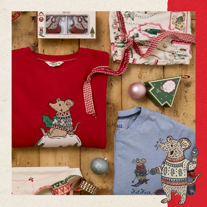 FatFace Christmas clothing flat lay featuring a red mouse sweatshirt, light blue graphic t-shirt, printed pyjama pants, and holiday ornaments.