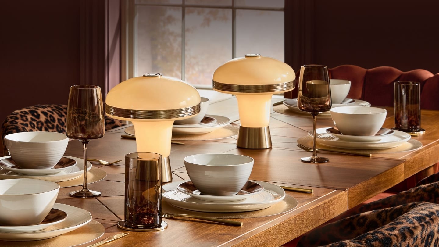 Dining table set with cream glass mushroom lamps, smoked glassware and leopard-print chairs