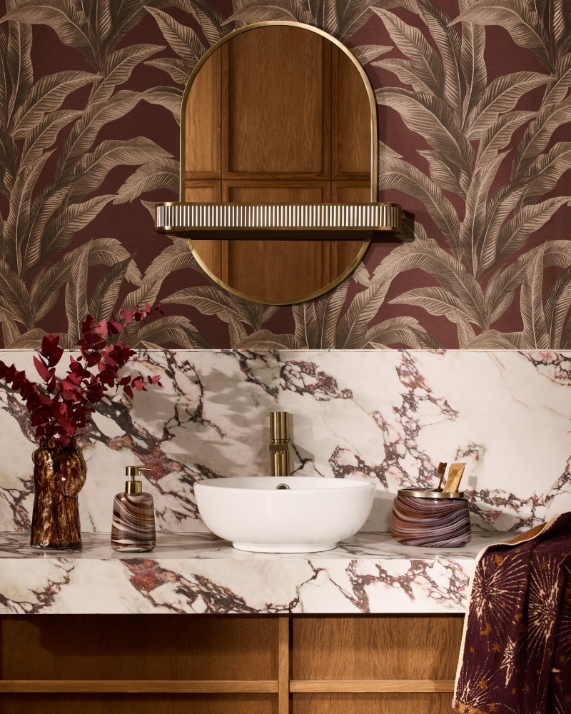 Marble vanity with an amber glass vase of red eucalyptus, a marbled soap dispenser and star print towels