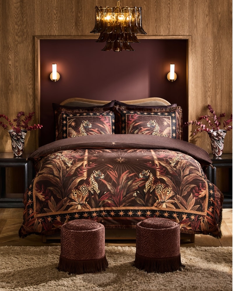 Bedroom with leopard print velvet bedding, brass wall lights and swirl glass vases